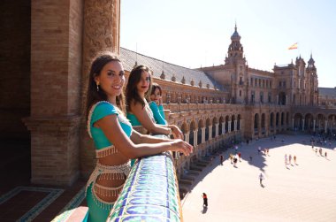 Üç dansçı bir balkonda dışarı bakıyor ve ufku işaret ediyor. Dansçılar güzel ve yetişkin. Dans ve arkadaşlık kavramı.
