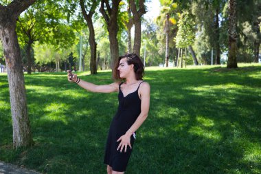 Genç Latin ve transseksüel kadın cep telefonuyla fotoğraf çekiyor. Kadın siyah bir elbise giyiyor. Farklılık, cinsiyet değiştirme ve homoseksüel ifade özgürlüğü kavramları.