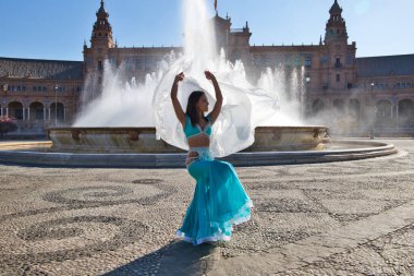 Meydanda dans eden genç ve güzel bir dansçı. O, elinde beyaz bir peçeyle açık mavi giyinmiş. Afrika ve Asya 'dan gelen dünya folklor kavramı.