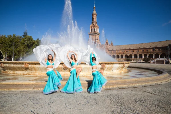 Açık mavi giyinmiş üç güzel dansçı şehir meydanında dans ediyor. Göbek dansı ve göbek dansı konsepti, Afrika folkloru..