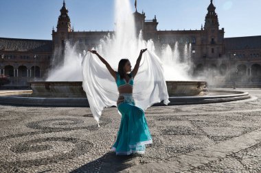 Meydanda dans eden genç ve güzel bir dansçı. O, elinde beyaz bir peçeyle açık mavi giyinmiş. Afrika ve Asya 'dan gelen dünya folklor kavramı.
