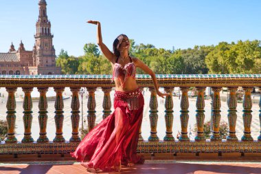 Genç ve güzel dansçı bir fotoğraf çekiminde kameraya poz veriyor. Kadın çok güzel ve geleneksel kıyafetler giyiyor. Güzellik, folklor ve göbek dansı konsepti.