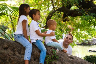 Parktaki bir ağacın gövdesine monte edilmiş üç küçük çocuğun portresi. Beyaz tişört ve kot giyiyorlar. Ablası transseksüel bir kız. Birleşmiş ve mutlu bir aile kavramı