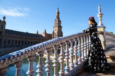 İspanyol, güzel, esmer flamenko dansçısı tipik siyah benekli flamenko elbisesi var. Sevilla 'da İspanya meydanında. Flamenko kavramı insanlığın kültürel mirası.