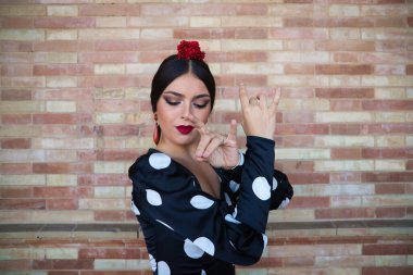 İspanyol, güzel, esmer flamenko dansçısı tipik bir flamenko elbisesi içinde beyaz benekli. Seville 'deki kahverengi tuğlaların üzerinde dans ediyor. Flamenko konsepti. İnsanlık mirası.