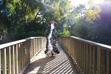 Tipik flamenko kostümlü güzel İspanyol esmer flamenko dansçısı kadın. Sokakta tahta bir podyumda dans eden beyaz benekli kadın. İnsanlığın Flamenko kültürel mirası.