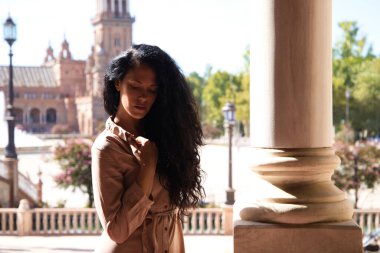 Güzel Latin kadın portresi, kıvırcık saçlı esmer, parkta yüzüyle değişik jestler ve ifadeler yapıyor. Farklı ifadeleri kavra.