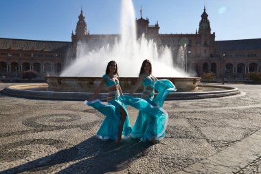 İki genç ve güzel dansçı çeşmenin önünde bir meydanda dans ediyorlar. Açık mavi giyinmişler ve ellerinde beyaz peçeler var. Afrika ve Asya 'dan gelen dünya folklor kavramı.