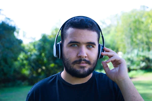 Yakışıklı, Latin, esmer, sakallı, yeşil gözlü bir adam bir çift kablosuz kulaklıkla müzik dinliyor. Boş zaman ve müzik kavramı.