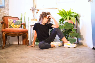 Stüdyoda yerde oturan güzel bir kadın fotoğraf çekimi için farklı mutluluk ve depresyon ifadeleri sergiliyor. Farklı ruh hallerini algıla.