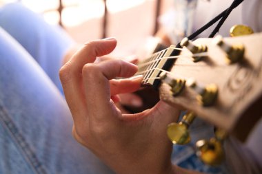 Ukulele çalan bir kadının ellerinin ayrıntıları. Yakın plan ve elin odak noktası ve arka planın odak dışı etkisi. Müzik konsepti