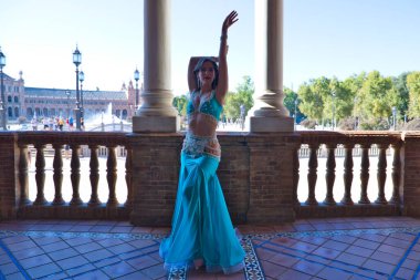 Genç ve güzel dansçı bir fotoğraf çekiminde kameraya poz veriyor. Kadın çok güzel ve geleneksel kıyafetler giyiyor. Güzellik, folklor ve göbek dansı konsepti.