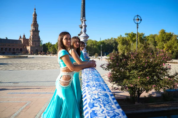 Açık mavi giyimli üç dansçı bir köprünün korkuluklarına yaslanıyorlar. Birbirleriyle konuşuyorlar ve kameraya bakıyorlar. Göbek dansı ve Hint dansı konsepti. Folklor