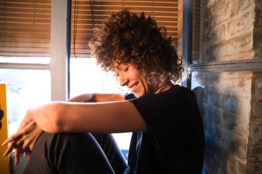 Stüdyoda büyük bir pencerenin kenarında oturan güzel bir kadın farklı neşe ve depresyon ifadeleri sergiliyor. Farklı ruh halleri kavramı.