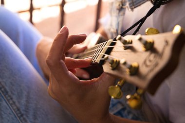 Ukulele çalan bir kadının ellerinin ayrıntıları. Yakın plan ve elin odak noktası ve arka planın odak dışı etkisi. Müzik konsepti