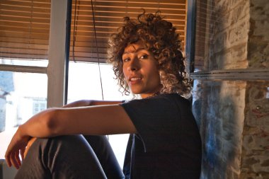 Stüdyoda büyük bir pencerenin kenarında oturan güzel bir kadın farklı neşe ve depresyon ifadeleri sergiliyor. Farklı ruh halleri kavramı.