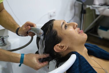 Uzman kuaför tarafından kuaförde saçı yıkanmış transseksüel bir kadın. Güzeller güzeli müşterimiz kuaförde masaj yaparken kendini rahat hissediyor..