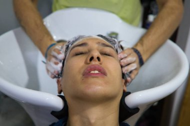 Uzman kuaför tarafından kuaförde saçı yıkanmış transseksüel bir kadın. Güzeller güzeli müşterimiz kuaförde masaj yaparken kendini rahat hissediyor..