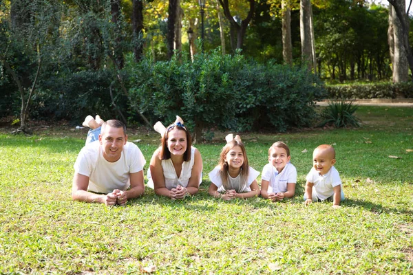 Portret Szczęśliwych Rodziców Trójką Dzieci Leżących Parku Białej Koszulce Dżinsach — Zdjęcie stockowe