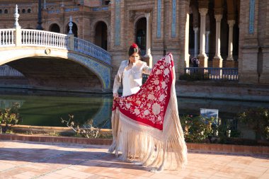 Flamenko dansçısı, kadın, esmer ve güzel tipik İspanyol dansçı Sevilla meydanında kırmızı bir manila şalıyla dans ediyor. İnsanlığın kültürel mirası Flamenko kavramı.