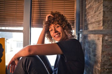 Stüdyoda büyük bir pencerenin kenarında oturan güzel bir kadın farklı neşe ve depresyon ifadeleri sergiliyor. Farklı ruh halleri kavramı.