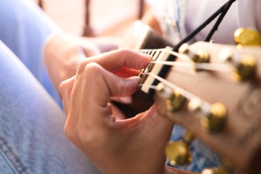 Ukulele çalan bir kadının ellerinin ayrıntıları. Yakın plan ve elin odak noktası ve arka planın odak dışı etkisi. Müzik konsepti