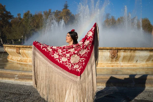 Flamenko dansçısı kadın, esmer ve güzel tipik İspanyol dansçı Seville meydanındaki bir çeşmenin önünde kırmızı bir manila şalıyla dans ediyor. İnsanlığın kültürel mirası Flamenko kavramı