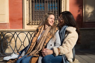 Lezbiyen çift kentteki devasa bir meydanda bankta oturuyor. Tatilde şehre geldiklerinde çok mutlu ve dinleniyorlar. Turizm ve seyahat kavramı. lgtb