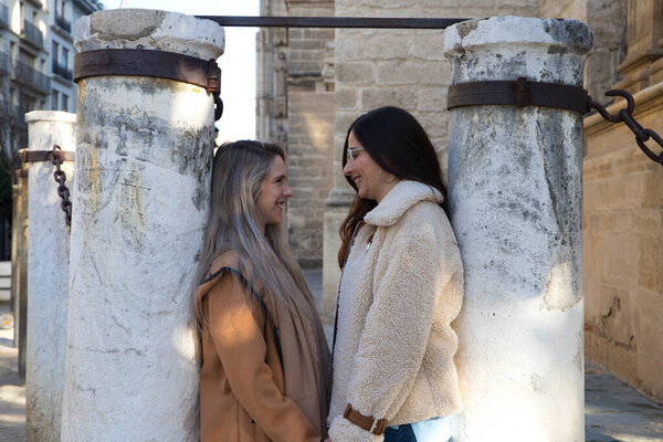 лесбийская пара опирается на колонны, окружающие готический собор. Женщины смотрят друг на друга с любовью и счастьем. Концепция однополых и лесбийских браков.