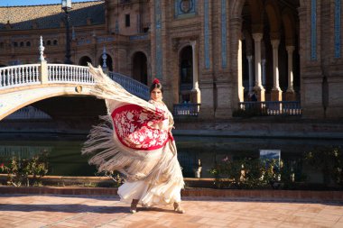 Flamenko dansçısı, kadın, esmer ve güzel tipik İspanyol dansçı Sevilla meydanında kırmızı bir manila şalıyla dans ediyor. İnsanlığın kültürel mirası Flamenko kavramı.