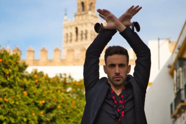 Siyah kastanyetlerle dans eden çingene adam kollarını portakal ağaçlarının arasına uzatarak poz veriyor ve arka planda da Seville Giralda var. İnsanlığın Flamenko kültürel mirası.
