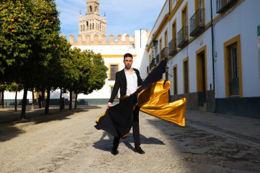 Siyah ve kırmızı ayakkabılar giymiş genç ve yakışıklı çingene bir adamın portresi Seville sokaklarında siyah ve sarı bir boğa güreşçisi peleriniyle dans ediyor. İnsanlığın Flamenko kültürel mirası.