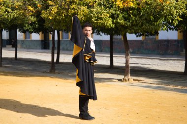 Siyah ve kırmızı ayakkabılar giymiş genç ve yakışıklı çingene bir adamın portresi Seville sokaklarında siyah ve sarı bir boğa güreşçisi peleriniyle dans ediyor. İnsanlığın Flamenko kültürel mirası.