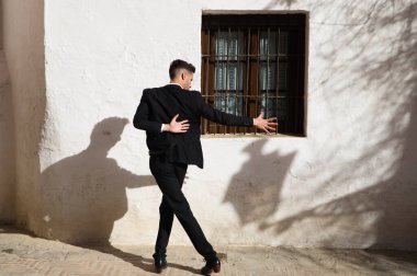 Genç ve yakışıklı çingene adam flamenko dansı yapıyor. Siyah ve yeşil yelek giyip Sevilla 'nın tipik Akdeniz sokaklarında flamenko dansı yapıyor. İnsanlığın Flamenko kültürel mirası