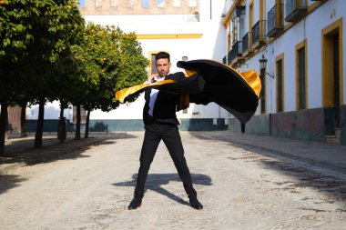 Siyah ve kırmızı ayakkabılar giymiş genç ve yakışıklı çingene bir adamın portresi Seville sokaklarında siyah ve sarı bir boğa güreşçisi peleriniyle dans ediyor. İnsanlığın Flamenko kültürel mirası.