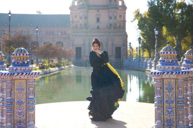 Siyah çingene kostümüyle flamenko yapan kadın sarı benekli ve saçlarında kırmızı çiçekli. Seville 'deki parkta dans ederken ellerini uzatıyor. İnsanlığın Flamenko kültürel mirası.