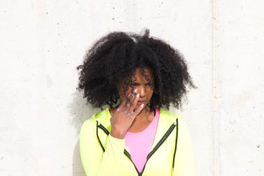 Gri beton duvar dokusu arka planında parlak yeşil ve pembe spor giyimli güzel Afro-Amerikalı kadın. Kadınlar farklı ifadeler kullanır. Gülen, ciddi, mutlu, üzgün, düşünen