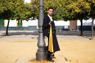 Siyah ve kırmızı ayakkabılar giymiş genç ve yakışıklı çingene bir adamın portresi Seville sokaklarında siyah ve sarı bir boğa güreşçisi peleriniyle dans ediyor. İnsanlığın Flamenko kültürel mirası.