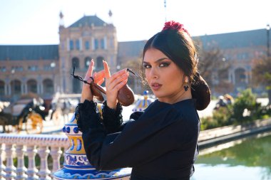 Siyah çingene kostümüyle flamenko dansı yapan bir kadının portresi. Sarı benekli, saçlarında kırmızı çiçek ve ellerinde kastanyetlerle. İnsanlığın Flamenko kültürel mirası kavramı.