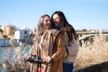 İki evli lezbiyen kadın balayı gezilerinde elektrikli scooter kullanıyorlar. Kadınlar genç ve yeni evliler. IgTB, eşcinseller ve lezbiyenler kavramını. Haklar ve eşitlik