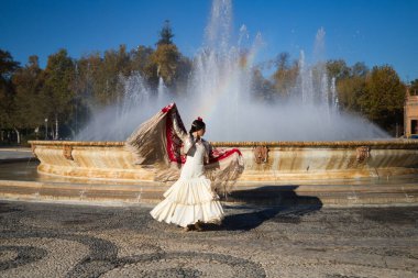 Flamenko dansçısı kadın, esmer ve güzel tipik İspanyol dansçı Seville meydanındaki bir çeşmenin önünde kırmızı bir manila şalıyla dans ediyor. İnsanlığın kültürel mirası Flamenko kavramı