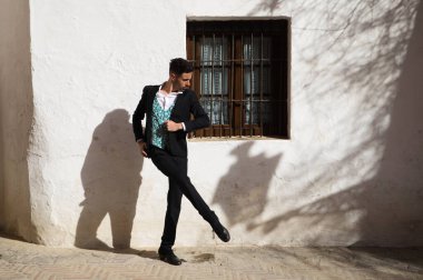 Genç ve yakışıklı çingene adam flamenko dansı yapıyor. Siyah ve yeşil yelek giyip Sevilla 'nın tipik Akdeniz sokaklarında flamenko dansı yapıyor. İnsanlığın Flamenko kültürel mirası