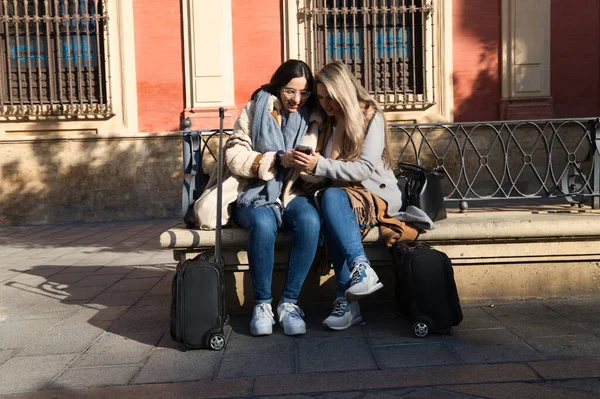 Lesbický Pár Sedí Lavičce Monumentálním Náměstí Městě Prohlížejí Své Mobilní — Stock fotografie