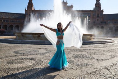 Meydanda dans eden genç ve güzel bir dansçı. O, elinde beyaz bir peçeyle açık mavi giyinmiş. Afrika ve Asya 'dan gelen dünya folklor kavramı.
