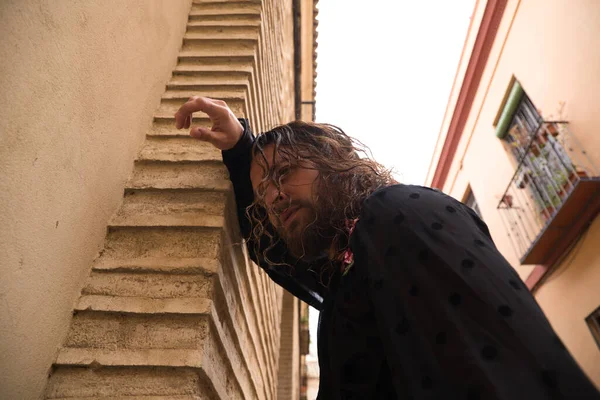 Uzun saçlı, siyah gömlekli ve kırmızı güllü flamenko dansı yapan bir adam kafasını Seville 'in tipik dar bir sokağının duvarına yaslar. Hayal kırıklığı, depresyon, üzüntü, iktidarsızlık, acı, tutku.