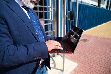 Olgun profesör, gri saçlı, sakallı, güneş gözlüklü, üniversiteye girmeden önce dizüstü bilgisayarına danışıyor. Eğitim ve öğretim kavramı. Öğretmenler ve emekliler.