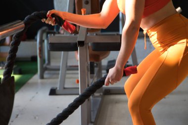 Genç atletik kadın spor salonunda bazı savaş halatlarıyla çapraz egzersizler yapıyor. Jimnastik, spor, ip, antrenman, atlet, egzersiz, egzersiz, egzersiz konsepti.