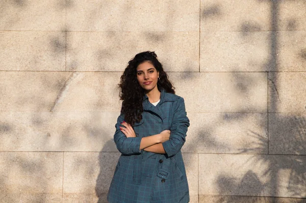 Kahverengi saçlı, kıvırcık burunlu, şık elbiseli güzel bir genç kadın kahverengi arka planda bir süper model olarak poz veriyor. Güzellik ve moda kavramı.