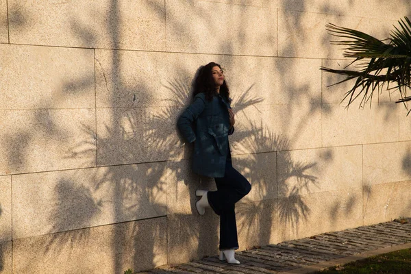 Kahverengi saçlı, kıvırcık burunlu, şık elbiseli güzel bir genç kadın kahverengi arka planda bir süper model olarak poz veriyor. Güzellik ve moda kavramı.