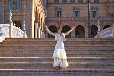 Flamenko dansçısı, kadın, esmer ve güzel tipik İspanyol dansçı Sevilla meydanında dans edip ellerini çırpıyor. İnsanlığın kültürel mirası Flamenko kavramı.